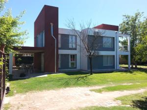 una casa con un albero davanti di Abuela Mari Apart Cabaña a Villa Cura Brochero