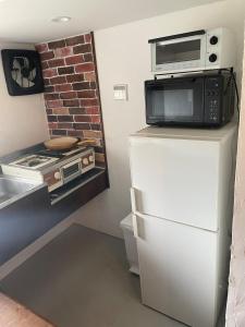 a kitchen with a microwave on top of a refrigerator at HANARE onomichi in Onomichi