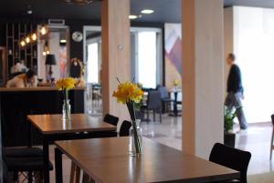 two tables with yellow flowers on them in a restaurant at Hotel Porta 26 in Skopje
