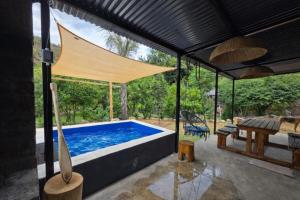 a pool with a canopy and a table and a bench at Luxury Unit with Mountain Views & Splash Pool in Oudtshoorn