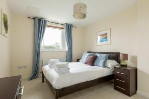 a bedroom with a bed with blue curtains and a window at Bay Retreat- Moments from Hamworthy Park in Poole