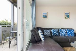 a brown leather couch in a room with a balcony at Bay Retreat- Moments from Hamworthy Park in Poole