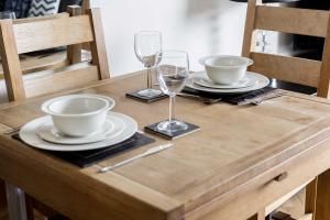 a wooden table with two plates and wine glasses on it at Bay Retreat- Moments from Hamworthy Park in Poole +13 photos