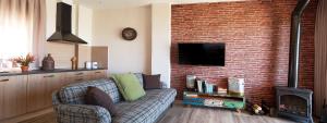 a living room with a couch and a brick wall at Casas Rurales Maribel - Complejo Moradas del Cerro 1 - Suites con Jacuzzi en Alcalá del Júcar in Casas del Cerro