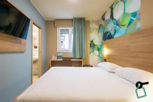 a bedroom with a large white bed and a tv at Hotiday Conegliano in Conegliano