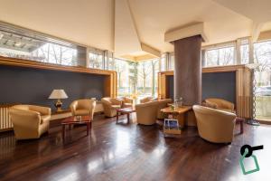 a waiting room with chairs and tables and windows at Hotiday Conegliano in Conegliano