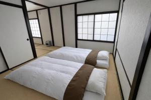 two beds in a room with two windows at 椴松 l フルリフォーム l 貸切の一軒家 l 千歳空港まで30分 l Todomatsu in Yuni +37 photos