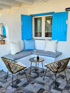 a patio with a blue bench and two chairs and a table at Jemphasis-New Apartments Mykonos in Agios Ioannis Mykonos
