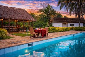 a dining table and chairs next to a pool at Muthu Mara River Lodge in Masai Mara