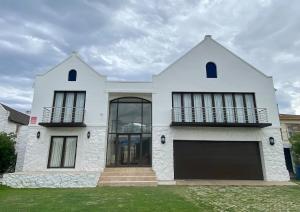a white house with a large garage at Iconic Villa in Arniston in Arniston