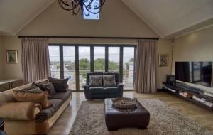 a living room with a couch and a tv at Iconic Villa in Arniston in Arniston