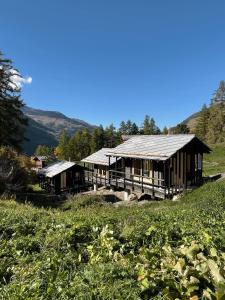 two large wooden buildings in a field of grass at minipockethouse in Evolène
