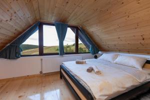 a bed in a room with a large window at Vikendice Kutlešić in Čajetina