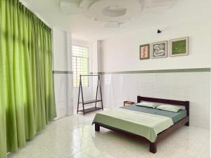 a bedroom with a bed and a green curtain at Nhà nghỉ Thu Hoạch in Hà Tiên