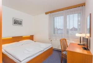 una camera da letto con un letto, una scrivania e una finestra di Hotel Astra a Praga