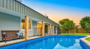 a swimming pool in front of a house at Escape on Eighth Poolside Comfort Close to CBD in Mildura