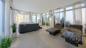 a room with a tub and two chairs and windows at Welle Resort, Sun & Snow in Grzybowo