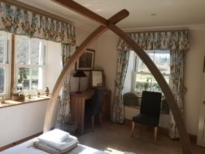 a bedroom with a bed and a desk and windows at South Lodge in Lochgilphead