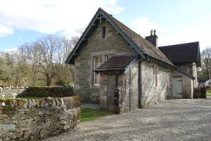 a stone house with a stone wall next to a driveway at School Room in Lochgilphead
