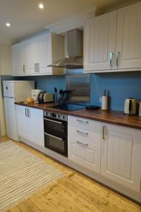 a kitchen with white cabinets and a stove top oven at School Room in Lochgilphead +5 photos