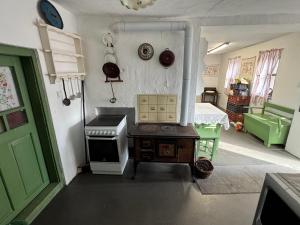 a kitchen with a stove and a green door at Kotlós Tanya in Zákányszék
