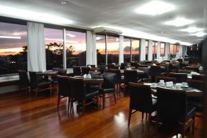 a restaurant with tables and chairs in a room with windows at Premium Vila Velha Ponta Grossa in Ponta Grossa