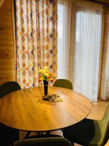 a wooden table with a vase of flowers on it at Cottage Dachi in Mestia in Mestia