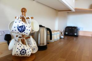 a bunch of coffee cups hanging on a wooden rack at The School House in Lochgilphead