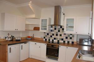 a kitchen with white cabinets and black and white tiles at The School House in Lochgilphead