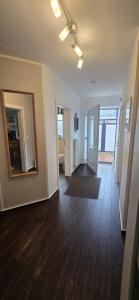 an empty living room with wood floors and a mirror at Perlmuschel in Borkum +34 photos