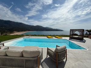 a swimming pool with chairs and a view of the ocean at villa la baies des anges in Calcatoggio