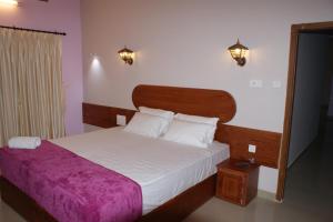 um quarto com uma cama grande e um cobertor roxo em Horn Bill Cottage em Thekkady