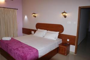 a bedroom with a large bed with a purple blanket at Horn Bill Cottage in Thekkady