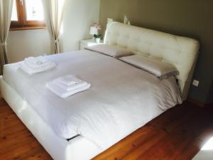- un lit blanc avec 2 serviettes dans l'établissement CHARLOTTE casa vacanze, à Villa di Chiavenna