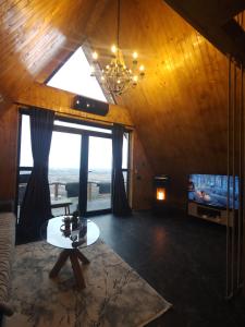 a living room with a chandelier and a couch and a tv at Cabana A-frame City View Târgoviște in Valea Voievoziilor