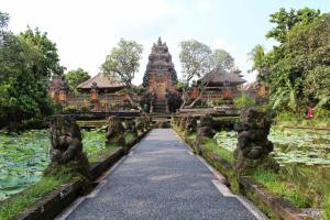 un chemin en face d'un temple avec un étang dans l'établissement Flora Apartment Bali, à Seminyak