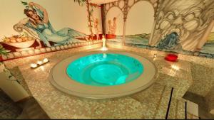 a bathroom with a blue tub with a painting on the wall at Hotel Boton D'Or & Wellness in La Thuile