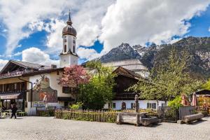 a building with a clock tower with mountains in the background at Ferienwohnung Haus Bader in Garmisch-Partenkirchen
