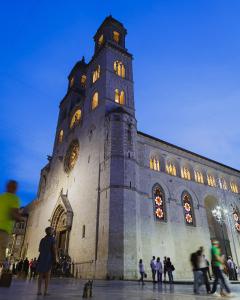 a large building with a clock tower with people standing outside at Hotel San Nicola in Altamura