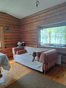 a living room with two couches and a dog sitting on a couch at Beautiful Cottage at Lake Saimaa, Rantamaja in Juva