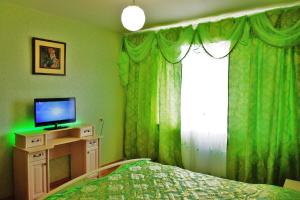 イヴァノヴォにあるApartments on Moskovskiy 21の緑のカーテン、ベッド、テレビが備わるベッドルーム1室が備わります。