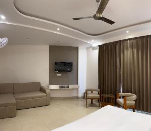 a bedroom with a bed and a couch and a tv at Hotel Ivory Hills in Kotdwāra
