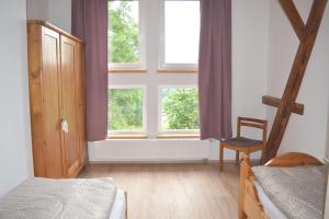 a bedroom with two beds and a chair and windows at Ferienwohnung Ruf in Küps +3 photos