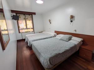 two beds are in a room with wooden floors at Akelarre Ostatua in Guernica y Luno