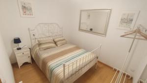 a white bedroom with a bed and a mirror at Apartamento Rural Sorribos (VUT-CO-004306) in Muros