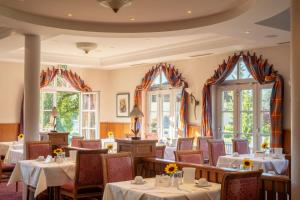 a dining room with tables and chairs and windows at Hotel Marko in Sankt Kanzian