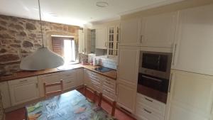 a kitchen with white cabinets and a stone wall at Apartamento Rural Sorribos (VUT-CO-004306) in Muros