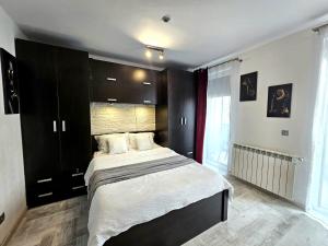 a bedroom with a large bed with black cabinets at The Solstice Studio Apartment in Cluj-Napoca
