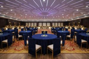 a large ballroom with blue tables and chairs at Hotel Amber Palace in Gurgaon