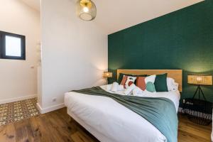 a bedroom with a large bed with a green wall at BLOOMY - Villa Biarritz in Biarritz